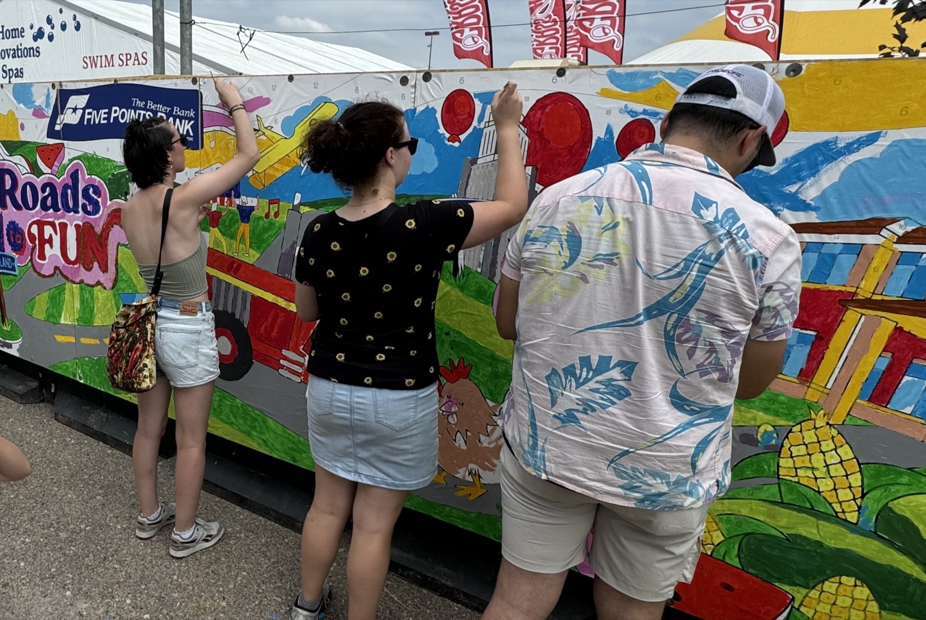 Event mural setup showing panels and participants painting
